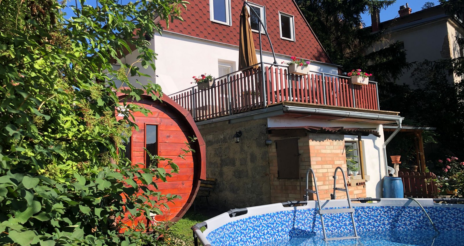 Fenced garden with a relaxation area with deck chairs, swimming pool, smokehouse and stylish log sauna.